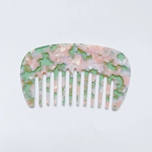Macro shot of marble textured acetate hair comb with mint green and pink pastel patterns