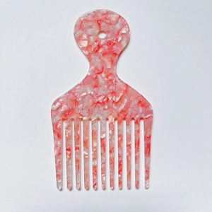 Detail of a pink and white marbled wide-tooth acetate comb for curly hair styling