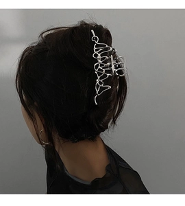 Détail d'une pince à cheveux en métal argenté liquide sur de longs cheveux sombres