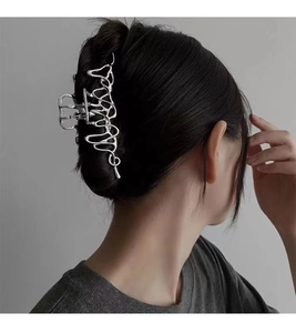 Détail d'une pince à cheveux argentée en métal liquide irrégulier sur une coiffure
