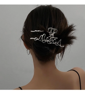 Vue détaillée d'une pince à cheveux argentée irrégulière en métal sur cheveux foncés