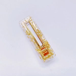 Macro detail of acrylic hair clip with gold foil flakes and metal spring mechanism