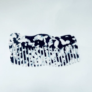 Close-up of black and white marble acetate hair comb with wavy edge and smooth teeth