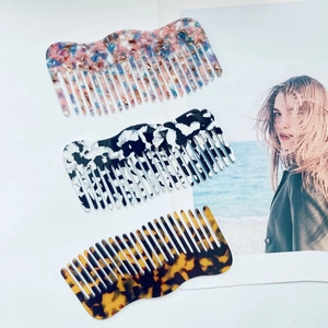 Three acetate hair combs with floral, ink, and tortoiseshell patterns in a wavy design