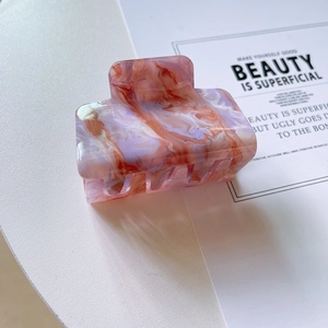 Vue détaillée d'une pince à cheveux motif marbre coloré sur un fond minimaliste chic