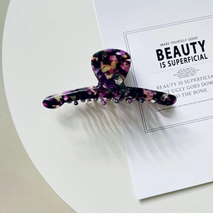 Détail d'une grande pince à cheveux en acétate au motif floral rétro sur table