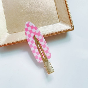 Close-up of pink and white checkered acetate hair clip on a golden decorative tray