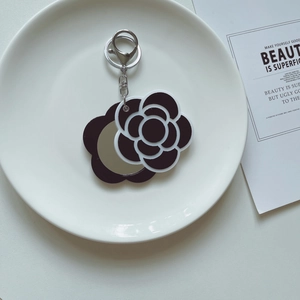 Macro view of portable camellia flower keychain mirror with silver metal clasp