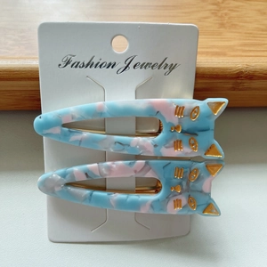 Detail of cat-shaped acetate hair clips with marble texture and gold accents