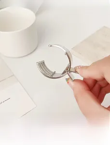 Detailed view of silver metal claw clip with polished finish held by hand
