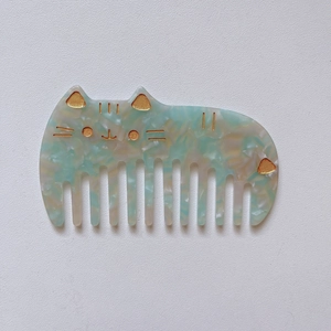 Detail of cute cat-shaped acetate hair comb with marble texture and gold accents