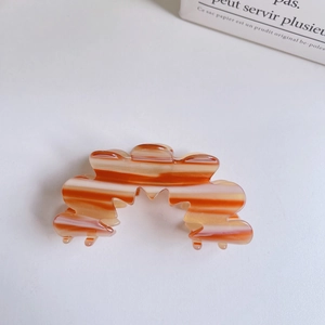 Detail of orange and white marble texture hair claw clip with wave-shaped teeth