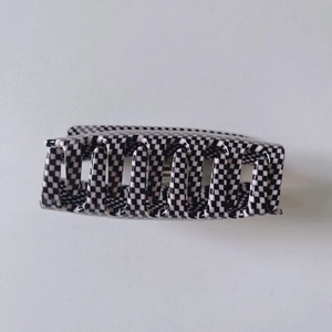 Close-up of a large acetate hair claw clip featuring a classic black and white checkerboard pattern