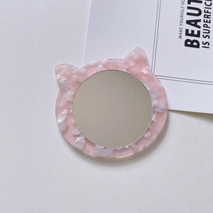 Close-up of a cat-shaped acetate vanity mirror with pink marble texture on a white background