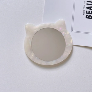 Macro detail of cat-eared portable makeup mirror with white pearlescent texture finish