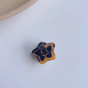 Macro d'une pince à cheveux en acétate en forme d'étoile avec motif smiley doré