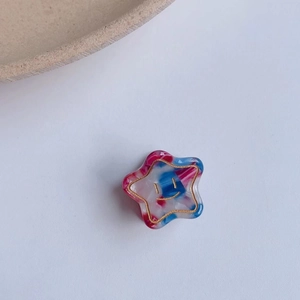 Détail d'une pince à cheveux étoile en acétate avec texture marbrée et motif smiley