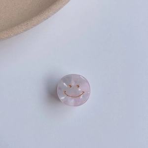 Dettaglio della molletta per capelli in marmo rosa con sorriso dorato elegante