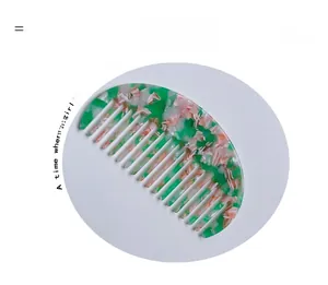 Dettaglio di un pettine a denti larghi in acetato con trama marmorizzata verde e rosa