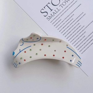 Détail d'une pince à cheveux dalmatien en acétate avec strass colorés et contours bleus