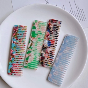 Gros plan de peignes portables en acétate marbré de couleurs variées sur une assiette
