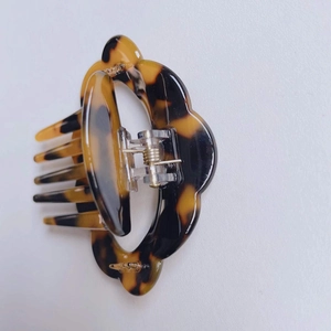 Detail view of acetate tortoise shell hair claw clip with unique wavy cloud-shaped edges