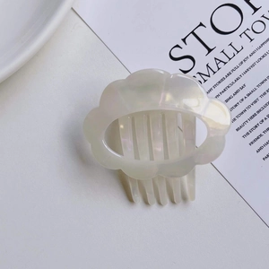 Close-up of pearl white acetate hair comb featuring an elegant wavy cloud design