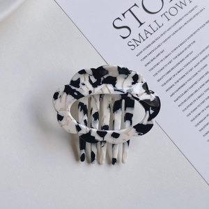 Close-up of cloud-shaped acetate hair clip with black and white marble pattern texture