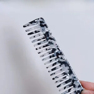 Detail of wide-tooth acetate hair comb with black and white marble pattern texture