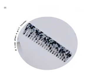 Detail of wide-tooth acetate comb with black and white tortoiseshell pattern on white stand