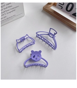 Detailed view of purple panda hair clip and matte accessories on a minimalist desk