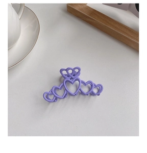 Close-up of a purple matte heart-shaped hair claw clip on a minimalist background