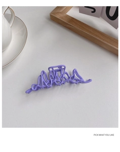 Detail view of a matte purple wavy hair claw clip on a minimalist white table setting