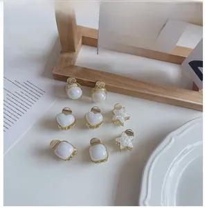 Détail de 7 mini pinces à cheveux dorées avec résine nacrée en forme de cœur et d'étoile