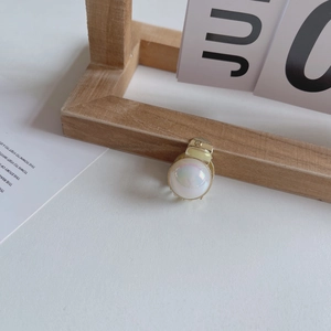 Détail macro d'une mini pince à cheveux perle avec finition irisée et base en métal doré