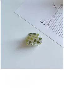 Détail de la petite pince à cheveux à damier vert et blanc avec une finition lisse