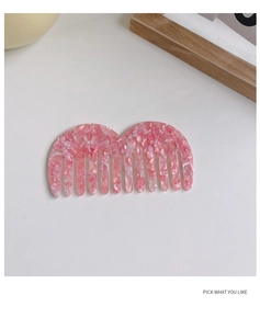 Dettaglio del pettine in acetato rosa marmorizzato a denti larghi con design a onde