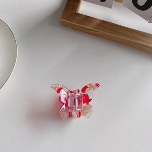 Detail of butterfly hair claw clip with pink and white marbled acetate finish and metal spring