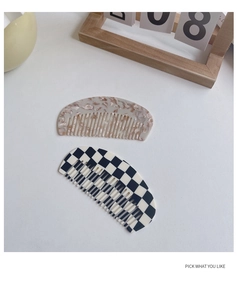 Close-up of pink marble and checkerboard acetate hair combs on a minimalist desk
