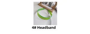 Detail of green striped acetate hair hoop on a white ceramic plate with soft lighting