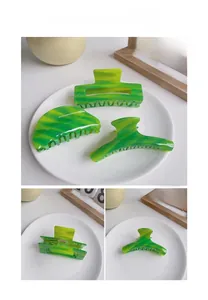 Detail view of green acetate hair claws showing marble texture and inner grip teeth