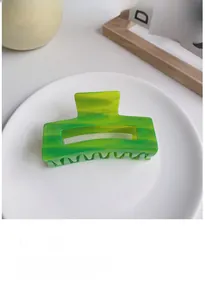 Detail of green and yellow marble patterned acetate hair claw clip on white tray