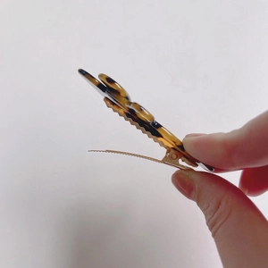 Detail showing tortoise shell acetate hair clip with golden metal base and jagged grip