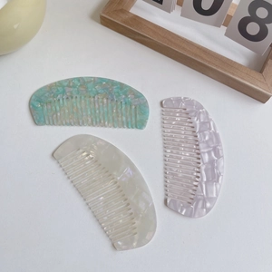 Three acetate tortoiseshell hair combs in mint green, pearl white, and lavender marble