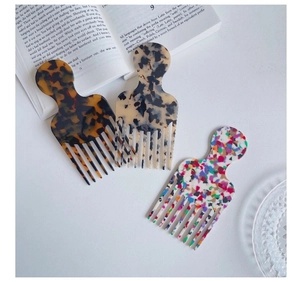 Three acetate hair picks with tortoiseshell and marble patterns on white background