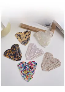 Macro display of six colorful heart-shaped acetate hair combs in various marble textures