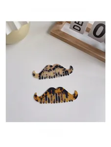Detail of two mustache-shaped acetate hair combs with tortoiseshell leopard pattern texture