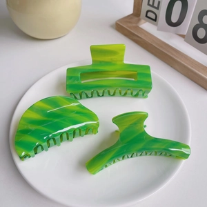 Three-piece set of green marble acetate hair claws with geometric shapes on white plate