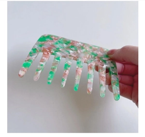 Detail view of anti-static wide-tooth hair comb with green marble pattern in acetate