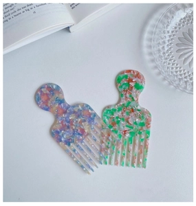 Detail of two acetate wide-tooth hair combs with marble textures on white background